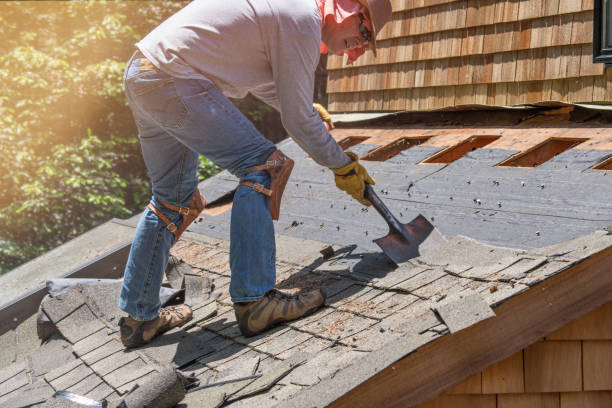 A man is removing roofing materials from a roof using a shovel.