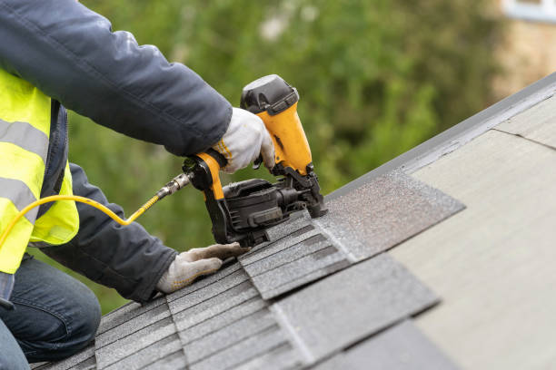 A man installs a roofing shingle using a nail gun during a roof repair project.