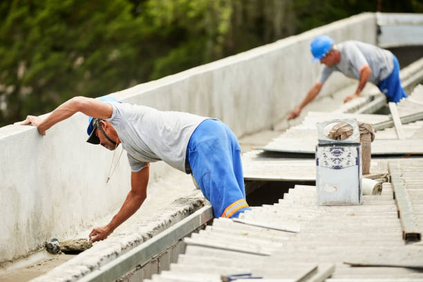 Two men working together to fix a concrete wall affected by storm damage and a roof leak.