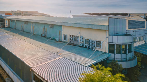 Industrial building featuring a large metal roof and numerous windows, showcasing the work of a metal roof installer.