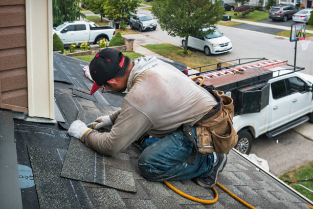 A man repairing a roof leak, using a hammer and tools to fix the damaged area.