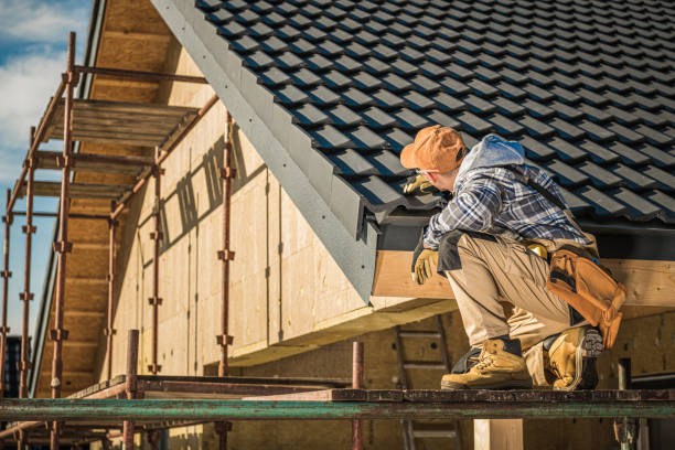 A man wearing a hard hat and work boots stands on a roof, preparing for re-roofing work.

