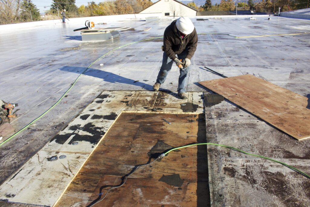 contractor evaluating flat roof repair vs replacement service on commercial building