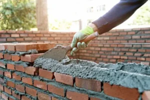 Experienced masonry contractors building a custom red brick wall using professional tools